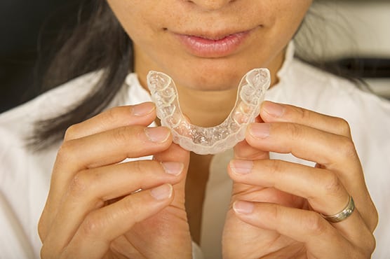 dental patient holding night mouthguard for teeth grinding