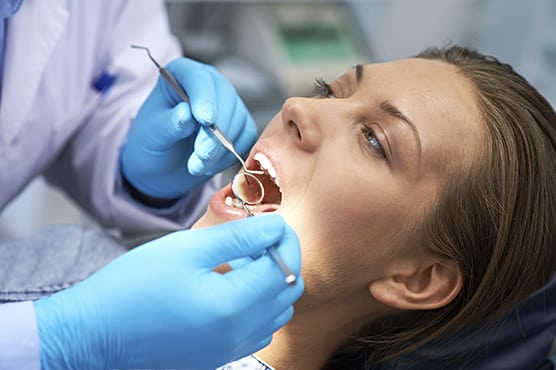 Dentist working in dental patents mouth with dental tools